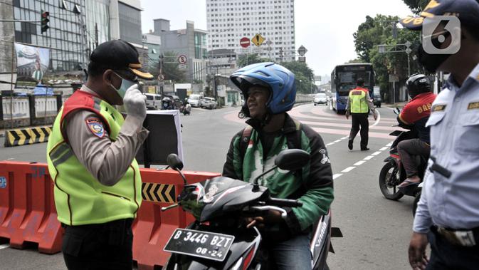 Petugas memberhentikan pengendara motor tanpa mengenakan masker di kawasan Menteng, Jakarta, Senin (13/4/2020). Batas maksimal 50 persen dari kapasitas kendaraan roda empat, berkendara dalam keadaan sakit, dan batas operasional kendaraan umum hingga pukul 18.00 WIB. (merdeka.com/Iqbal S. Nugroho)