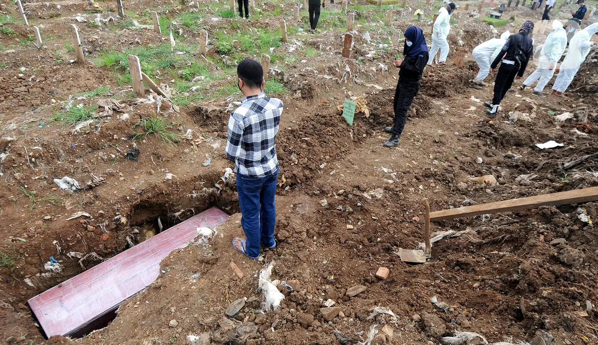 Kerabat mengumandangkan adzan saat pemakaman korban Covid-19 di TPU Srengseng Sawah 2, Jagakarsa, Jakarta, Senin (17/5/2021). Hari ini seluruh TPU di wilayah DKI dibuka untuk umum dengan menerapkan protokol kesehatan seperti pembatasan pengunjung dan waktu berziarah. (merdeka.com/Arie Basuki)