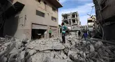 Anak-anak Palestina berjalan di tengah reruntuhan bangunan yang hancur akibat serangan Israel di kamp pengungsi Bureij di Jalur Gaza bagian tengah pada 27 April 2025. (Eyad BABA/AFP)