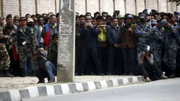 Warga dijaga oleh petugas saat melihat proses pengamanan benda mencurigakan dipinggir jalan kompleks kantor Singha Durbar, Nepal, (1/3). Daerah tersebut dekat dengan rumah kantor Perdana Menteri dan departemen lain. (REUTERS / Navesh Chitrakar)