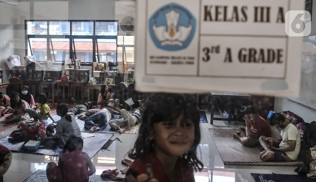 Aktivitas warga korban banjir saat mengungsi di salah satu ruang kelas SDN 01 Kampung Melayu, Jakarta, Minggu (21/2/2021). Selama pandemi virus corona, pihak kelurahan menyiapkan pengungsian di lantai 1 dan 2 serta membatasi 50 persen kapasitas pengungsi. (merdeka.com/Iqbal S Nugroho)