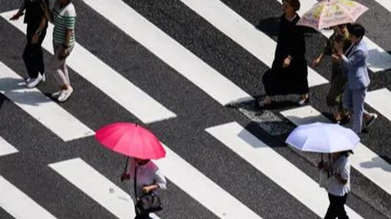 Pejalan kaki menggunakan payung saat menyeberangi jalan di Seoul, Korea Selatan, Rabu&nbsp;(14/8/2024). Gelombang panas ekstrem tengah melanda sebagian besar wilayah Korea Selatan. Foto: Anthony Wallace/AFP
