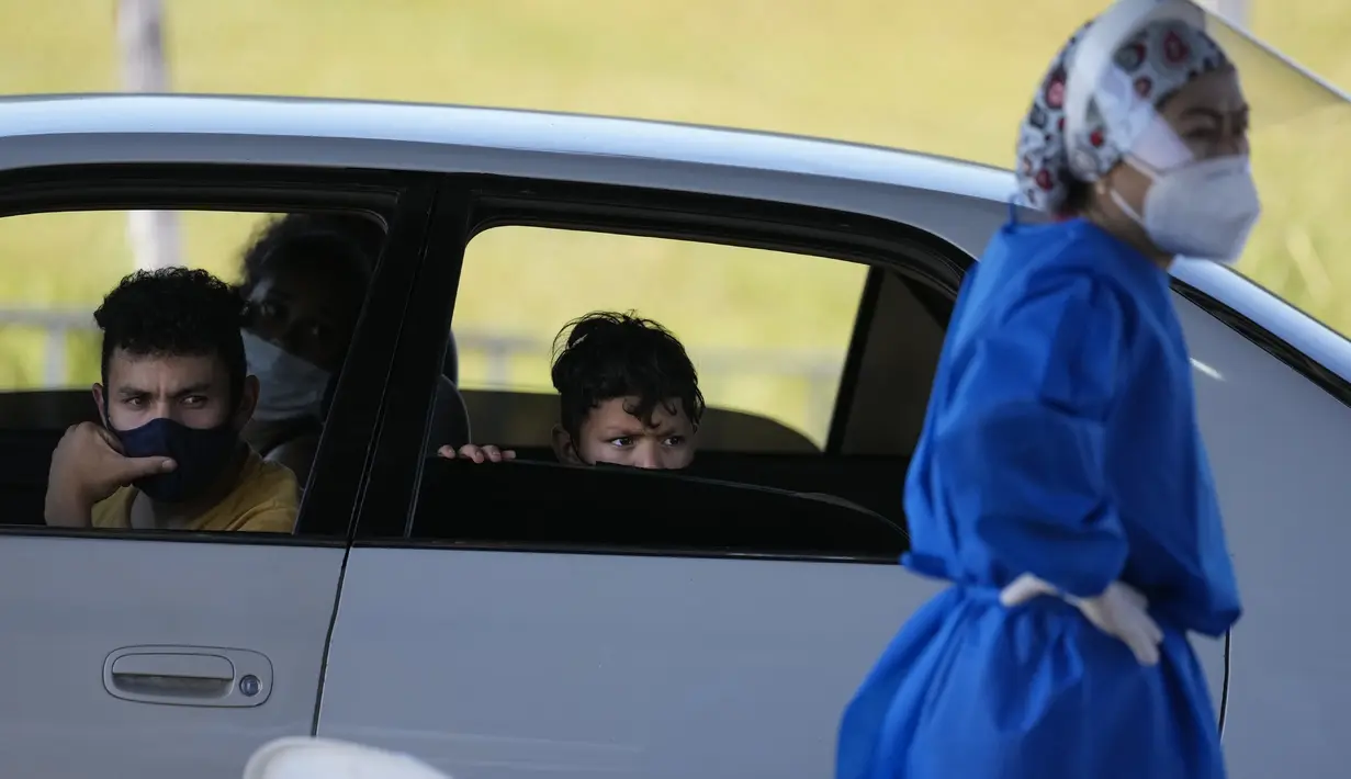 Anggota keluarga menunggu untuk diuji COVID secara gratis di tempat pengujian drive-thru di arena pacuan kuda di Capiata, Paraguay, Selasa (11/1/2022).  (AP Photo/Jorge Saenz)