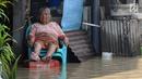 Seorang warga duduk di depan rumahnya yang tergenang banjir di kawasan Sawah besar Semarang, Jawa Tengah, Sabtu (8/12). Akibat banjir tersebut Warga pun menyelamatkan diri tanpa sempat membawa barang pribadi miliknya. (Liputan6.com/Gholib)
