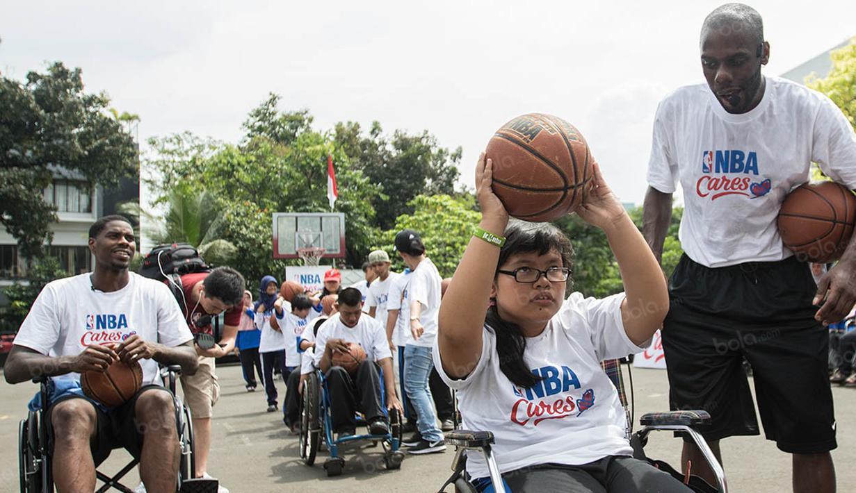 Perwakilan NBA Asia, Chris Sumner, menyemangati seorang penyandang disabilitas untuk melempar bola. (Bola.com/Vitalis Yogi Trisna)