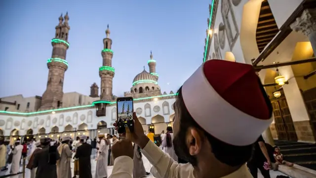 Seorang jamaah dari Afghanistan mengambil foto saat shalat Idul Fitri di masjid al-Azhar di Kairo.