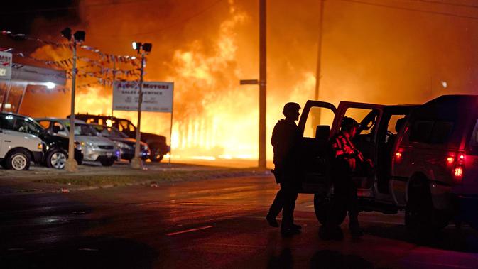 Polisi mencoba mengamankan bisnis setelah pengunjuk rasa membakar sebuah kantor di Kenosha, Wisconsin, Amerika Serikat, Senin (24/8/2020). Protes dipicu oleh penembakan Jacob Blake oleh petugas polisi Kenosha sehari sebelumnya. (AP Photo/David Goldman)