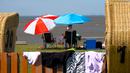 Warga duduk di bawah payung saat suhu mencapai 34 derajat Celcius di dekat pantai Laut Utara di Wremen, Jerman barat (24/7/2019). Peramal cuaca memprediksi suhu tertinggi di seluruh Eropa barat yang terkena gelombang panas akan mencetak rekor suhu terbaru.  (AFP Photo/Patrik Stollarz)