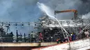 Petugas pemadam kebakaran dibantu pekerja mencoba memadamkan api di kapal nelayan di Pelabuhan Benoa, Denpasar, Bali, Senin (9/7). Hingga saat ini tak ada korban jiwa dalam kebakaran tersebut. (SONNY TUMBELAKA/AFP)