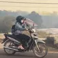 Pengendara bermotor mengunakan masker saat melintasi jalan yang diselimuti kabut asap di Kota Palangka Raya, Kalimantan Tengah, Kamis,  20 Agustus 2026. (AFP/ Reina)