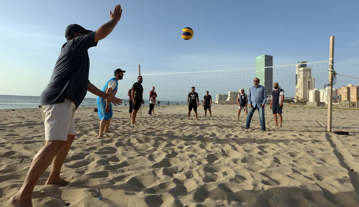 Orang-orang bermain voli pantai sembari menunggu waktu berbuka puasa selama bulan suci Ramadan, meskipun lockdown karena pandemi COVID-19, di ibu kota Tripoli, Libya pada Jumat (8/5/2020). (Photo by Mahmud TURKIA / AFP)