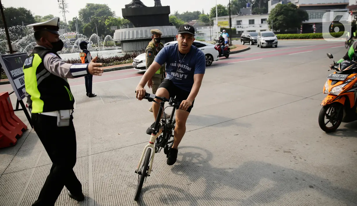 Petugas gabungan melakukan pengalihan jalur pesepeda di kawasan Sudirman-Thamrin, Jakarta, Minggu (5/9/2021). Pemberlakuan jalur ganjil genap pada masa PPKM membuat pengguna sepeda dilarang melintasi kawasan ganjil-genap pagi ini. (Liputan6.com/Angga Yuniar)
