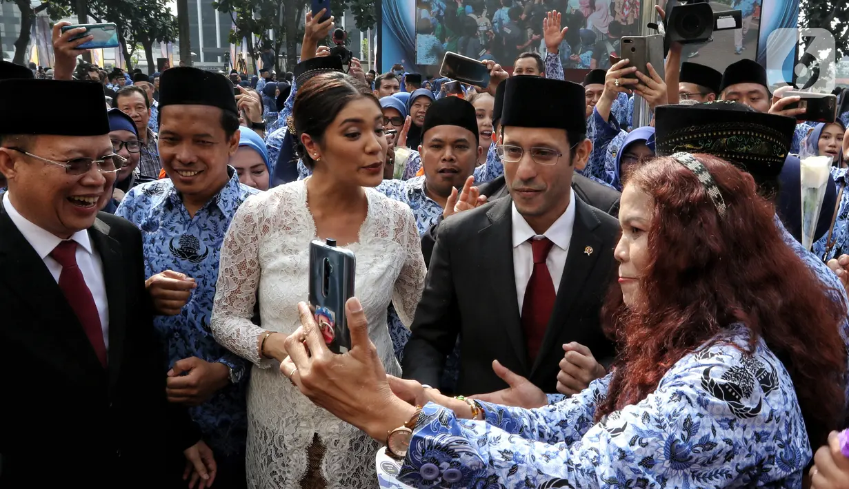 Menteri Pendidikan dan Kebudayaan (Mendikbud) Nadiem Makarim didampingi istri Franka Franklin usai mengikuti Upacara Peringatan HUT PGRI ke-74 dan Hari Guru Nasional 2019 di Kemendikbud, Jakarta, Senin (25/11/2019). (Liputan6.com/Johan Tallo)