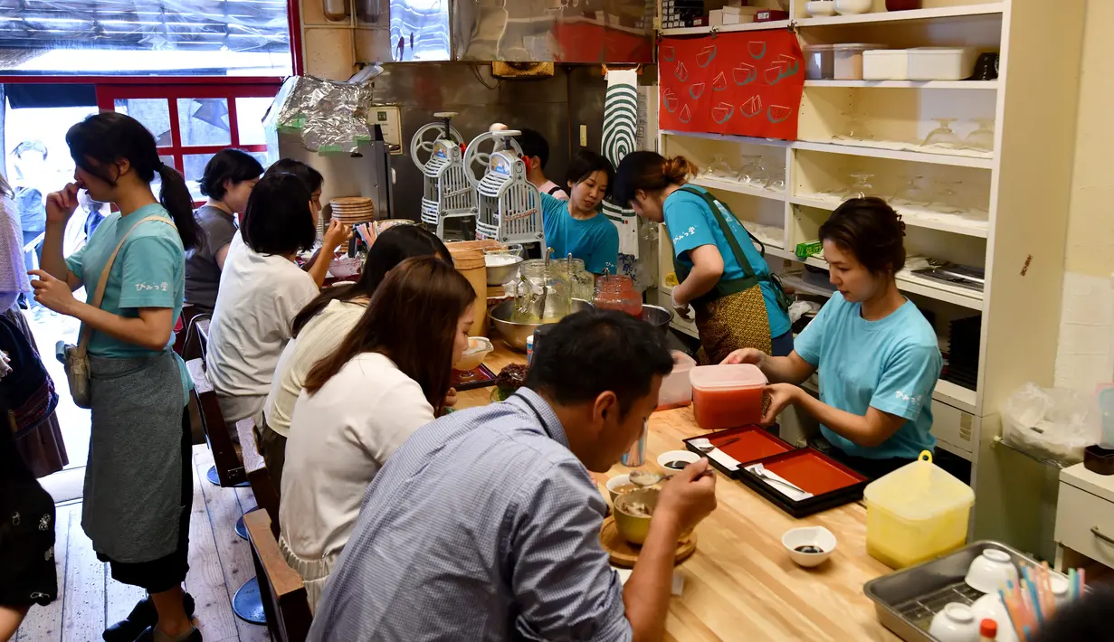 Pelanggan menikmati kakigori atau es serut di distrik Yanaka Tokyo, Jepang (21/6/2019). makanan penutup musim panas yang menyegarkan ini terbuat dari campuran es serut, sirup buah dan susu kental manis. (AFP Photo/Toshifumi Kitamura)