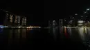 Foto kombinasi menunjukkan pemandangan umum hotel dan resor Marina Bay Sands yang diterangi (kiri) dan cakrawala kota sebelum (atas) dan setelah lampu dimatikan (bawah) selama Earth Hour di Singapura (27/3/2021). (AFP/Roslan Rahman)