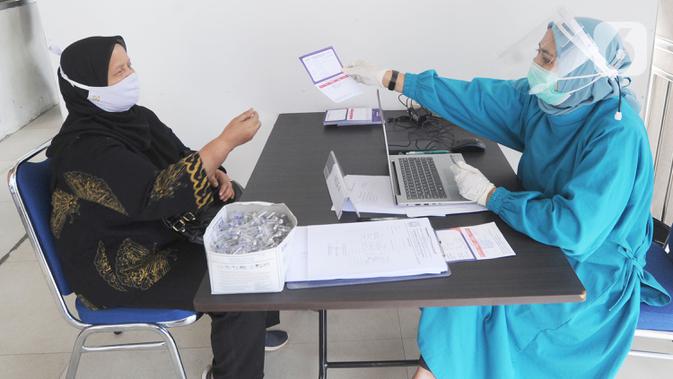 Petugas memberikan kartun vaksin kepada tenaga kesehatan berusia lanjut di Puskesmas Kecamatan Jagakarsa, Jakarta, Kamis (11/2/2021). Sekitar 11 ribu nakes lansia yang berusia di atas 60 tahun menjadi prioritas penerima vaksin untuk mengurangi resiko atas infeksi covid-19. (merdeka.com/Arie Basuki)