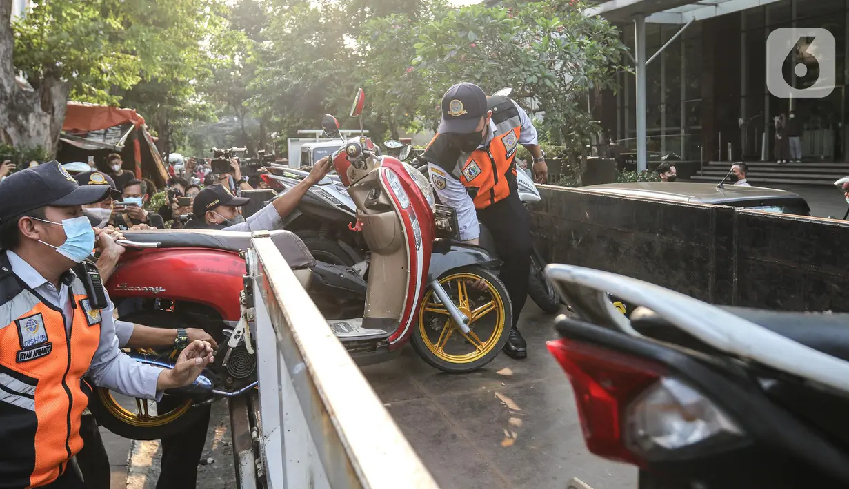 Petugas gabungan yang terdiri dari Satpol PP dan Dinas Perhubungan (Dishub) DKI Jakarta mengangkut motor yang terjaring razia ke atas truk di lokasi Citayam Fashion Week, kawasan Stasiun Dukuh Atas, Sudirman, Selasa (26/7/2022). Dishub DKI Jakarta mengamankan sebanyak 16 sepeda motor yang terpakir secara liar. (Liputan6.com/Faizal Fanani)