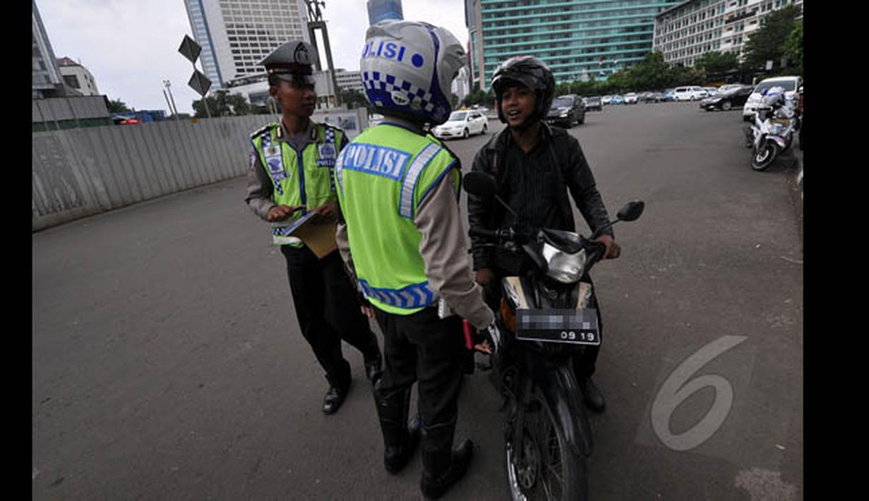 Petugas kepolisian saat memberhentikan pengendara motor ketika melintas di Jalan MH Thamrin, Jakarta, Minggu (18/1/2015). (Liputan6.com/Miftahul Hayat)