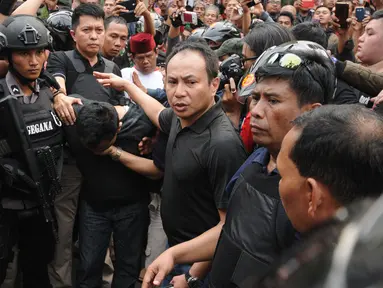 Petugas kepolisian menggiring salah satu tersangka perampokan disertai penyanderaan di Kawasan Pondok Indah, Jakarta, Minggu (3/9). Perampokan disertai penyanderaan terjadi sejak Minggu (3/9) pagi. (Liputan6.com/Helmi Fithriansyah)