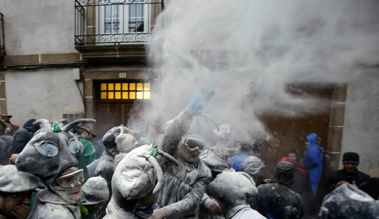 Peserta melemparkan tepung ke peserta lain dalam Festival O Entroido di Laza, Spanyol, Senin (8/2). Festival yang berlangsung selama seminggu itu dianggap sebagai peristiwa sosial dan budaya utama di kota Laza. (REUTERS/ Miguel Vidal)