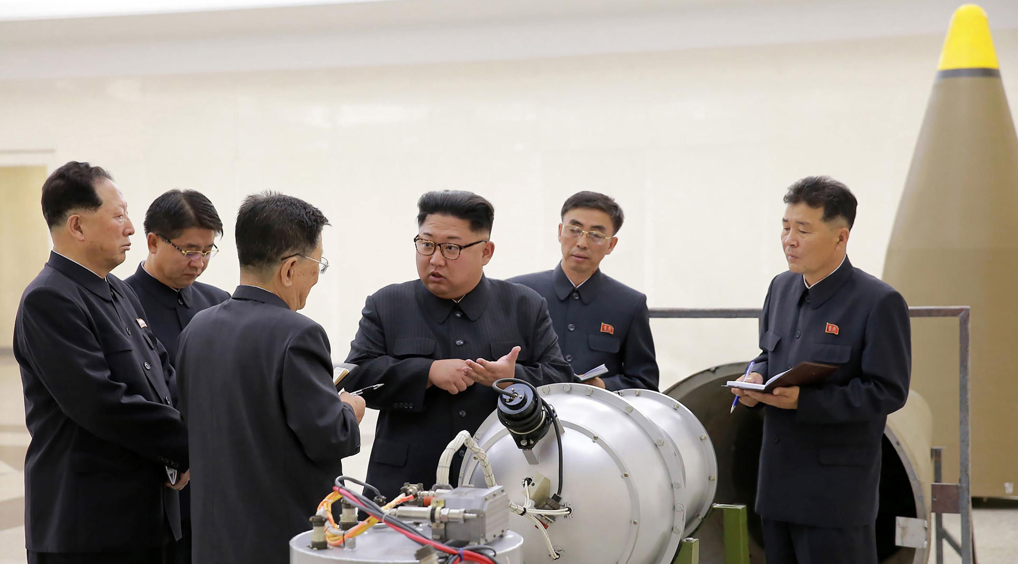 Pemimpin Korut, Kim Jong-un berbincang dengan para peneliti mengenai program senjata nuklir saat meninjau pembuatan bom hidrogen yang dapat dimasukkan ke dalam rudal balistik antarbenua pada 3 September 2017. (AFP Photo/Kcna Via Kns/Str)