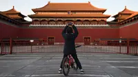 Seorang anak laki-laki mengambil foto di luar Kota Terlarang yang ditutup di Beijing pada Selasa (4/2/2020). Mencegah korban virus corona bertambah, China menutup  banyak destinasi wisata termasuk Kota Terlarang yang ditutup untuk kunjungan wisatawan sejak 24 Januari 2020 lalu. (GREG BAKER/AFP)