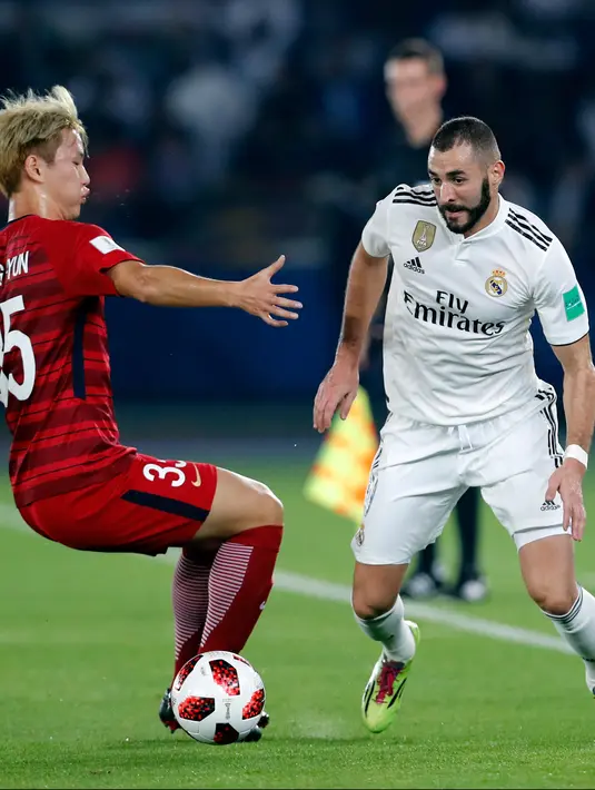 Striker Real Madrid, Karim Benzema berusaha melewati pemain Kashima Antlers, Seunghyun Jung selama semifinal Piala Dunia Antarklub 2018 di stadion Zayed Sports City, Uni Emirat Arab (19/12). Madrid menang 3-1. (AP Photo/Hassan Ammar)