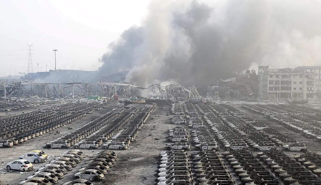 Kepulan asap masih terlihat diantara puing kendaraan di lokasi ledakan di pelabuhan Kota Tianjin, China, Kamis (13/8/2015). Ledakan yang diperkirakan berkekuatan setara 21 ton TNT ini menewaskan 17 orang dan ratusan lainya terluka. (REUTERS/China Daily)