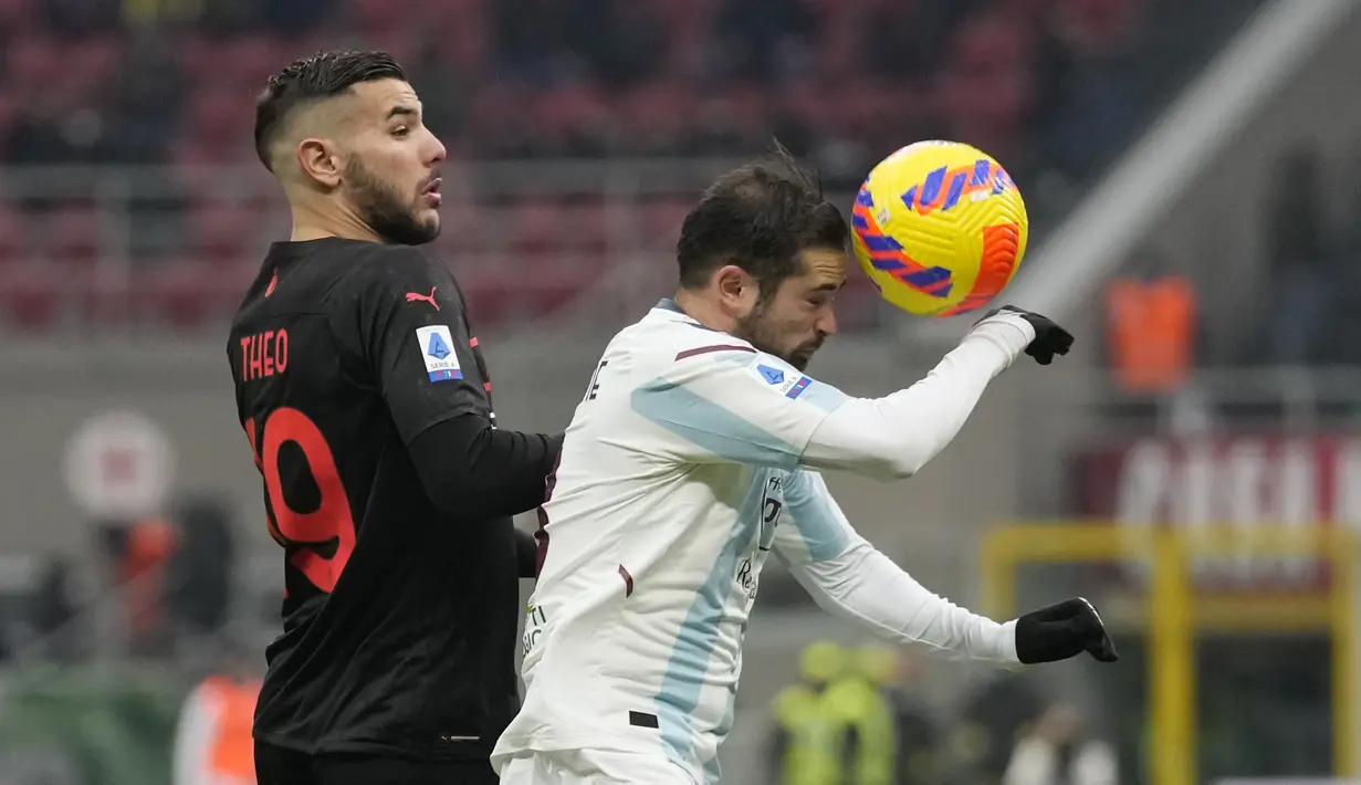 Bek AC Milan, Theo Hernandez berebut bola dengan pemain Salernitana, Andrea Schiavone pada pertandingan lanjutan Liga Serie A Italia di stadion San Siro, di Milan, Italia (4/12/2021). AC Milan menang atas Salernitana dengan skor 2-0. (AP Photo/Antonio Calanni)