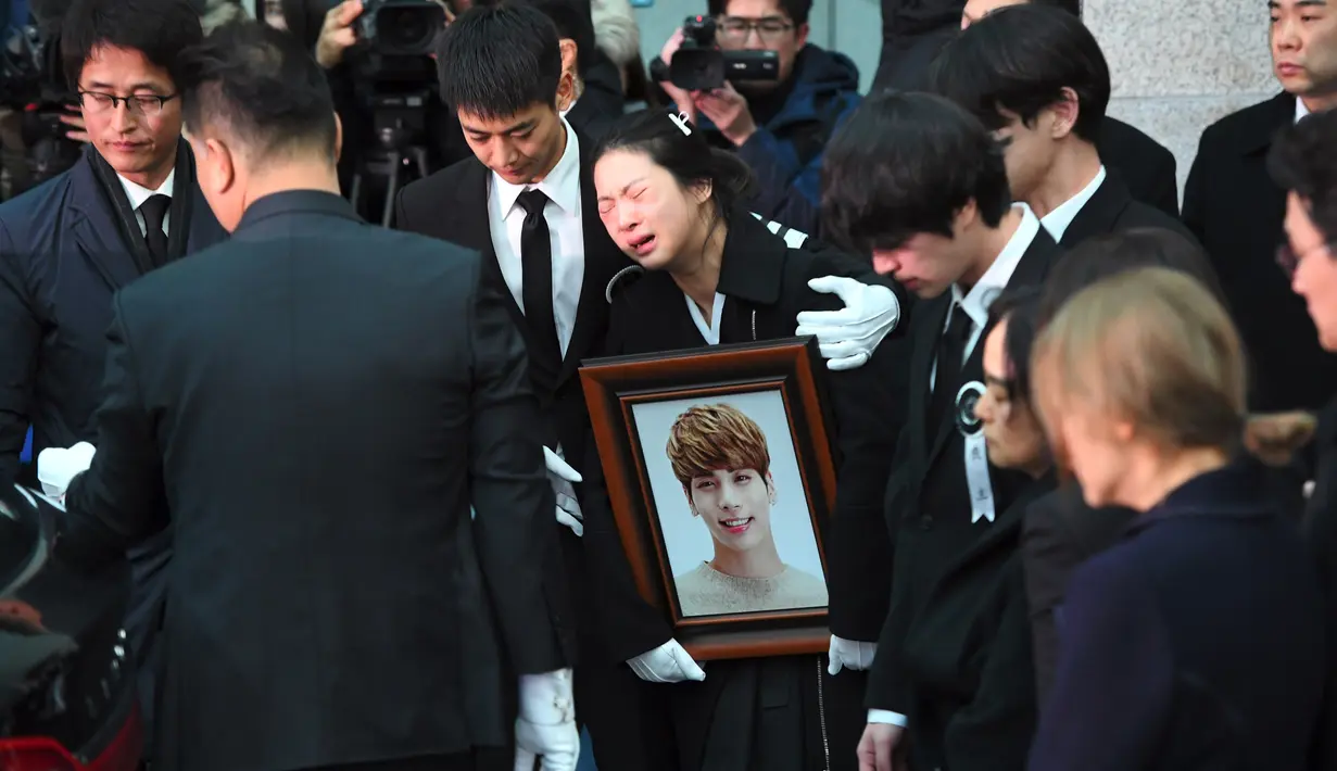 Kakak Jonghyun menangis dalam pelukan Minho SHINee saat peti jenazah dimasukkan ke mobil menuju tempat pemakaman dari rumah persemayaman di Asan Hospital, Seoul, Kamis (21/12). Kesedihan menyelimuti pelepasan peti jenazah Jonghyun. (JUNG Yeon-Je/AFP)