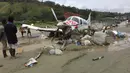 Sebuah pesawat twin otter rusak pasca terseret banjir bandang dan menutupi lapangan terbang di Kabupaten Sentani, Jayapura, (17/3). Banjir bandang Sentani menewaskan 70 orang dan puluhan luka-luka. (AFP/Netty Dharma Somba)