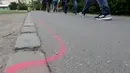 Seorang pria berjalan melewati garis berwarna pink yang diperuntukkan bagi bandar narkotika di Taman Goerlitzer, Berlin, 9 Mei 2019. Nantinya, para bandar hanya boleh bertransaksi di dalam zona berupa coretan kotak dengan cat semprot berwarna pink itu saja. (AP Photo/Michael Sohn)