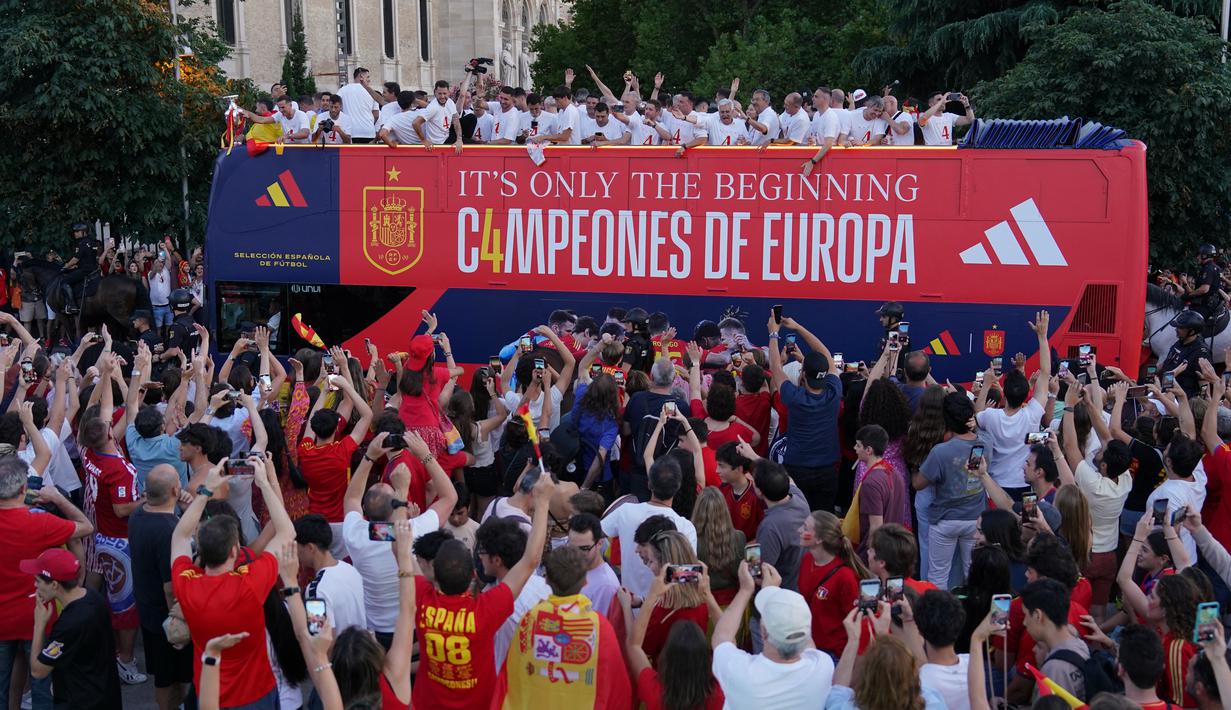 Para pemain dan staf pelatih naik bus atap terbuka untuk berparade melintasi pusat Kota Madrid. (CESAR MANSO / AFP)