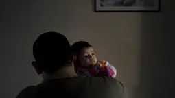 Diego Roman menggendong putrinya, Victoria Soto, untuk berfoto di Lomas de Zamora, Argentina pada 4 Juli 2021. Victoria yang lahir pada 13 April 2021 kehilangan ibunya, Elizabeth Soto, yang meninggal dunia akibat COVID-19 beberapa hari kemudian. (AP Photo/Natacha Pisarenko)