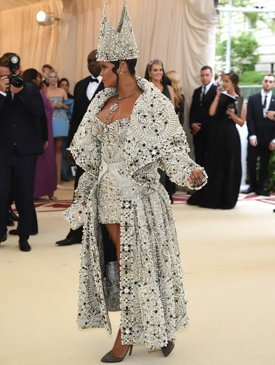 Penyanyi Rihanna menghadiri pagelaran Met Gala 2018 di Museum Seni Metropolitan New York, Senin (7/5). Rihanna mengenakan gaun pendek strapless yang seksi dilengkapi jubah berukirkan kristal dan mutiara. (Evan Agostini/Invision/AP)