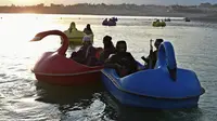 Sejumlah pasukan Taliban saat menaiki perahu kayuh di Danau Qargha di sebuah pekan raya di Kabul barat (28/9/2021). Sambil membawa senjata laras panjang sambil berjaga, mereka mengayuh perahu bebek memutari danau. (AFP/Wakil Kohsar)