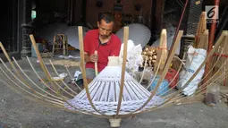Seorang perajin membuat payung kertas di Desa Tanjung, Kecamatan Juwiring, Klaten, Kamis (11/10). Para perajin menjadikan usaha payung hias sebagai tulang punggung ekonomi keluarga. (Liputan6.com/Gholib)