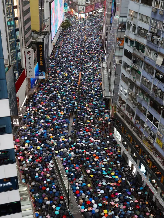 Pengunjuk rasa membawa payung saat menuju Victoria Park, Hong Kong, Minggu (18/8/2019). Puluhan ribu massa pro-demokrasi membawa payung saat hujan mengguyur Victoria Park dan sekitarnya. (AP Photo/Vincent Yu)