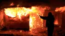 Imigran berdiri di depan tempat tinggalnya yang dibakar pihak berwenang di lahan kumuh yang dijuluki "Jungle" di Calais, Prancis (1/3). Pembakaran ini memunculkan protes bagi ribuan imigran yang tinggal di lokasi tersebut. (REUTERS/Pascal Rossignol)