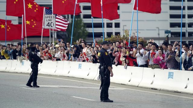 Sejumlah warga mengibarkan bendera AS dan China di sekitar lokasi KTT APEC, Selasa (14/11/2023). (AP/Evan Vucci)