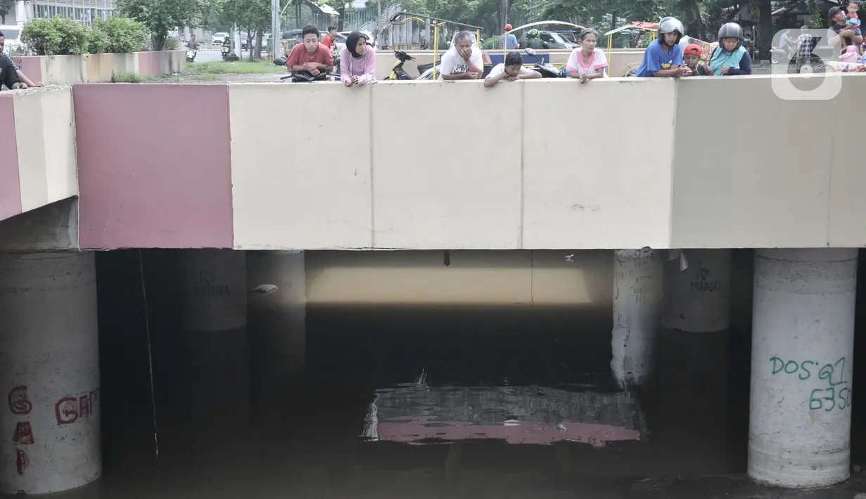 Warga melihat kondisi underpass Kemayoran yang masih terendam bajir di Jakarta Pusat, Minggu (26/1/2020). Ketinggian air yang masih merendam underpass Kemayoran mencapai 1,5 meter. (merdeka.com/Iqbal S Nugroho)