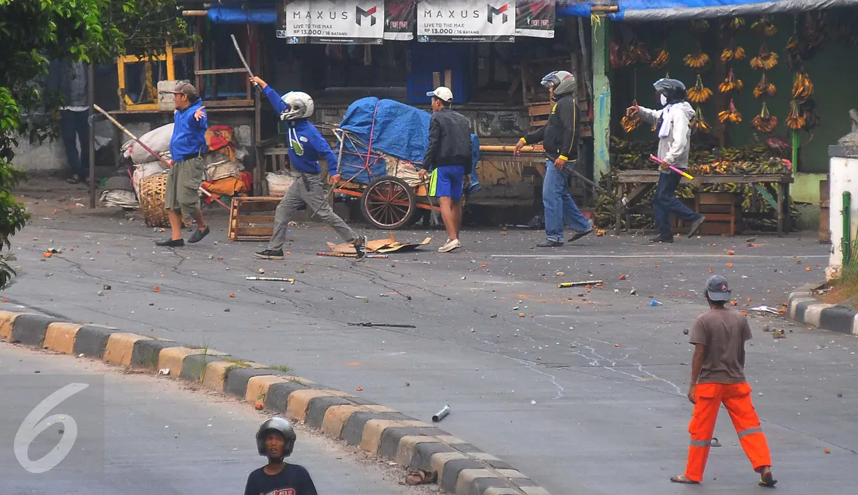 Sejumlah warga tampak membawa senjata tajam ketika Dua kelompok warga terlibat tawuran di dekat Stasiun Manggarai, Jakarta Selatan, Minggu (8/1). (Liputan6.com/Angga Yuniar)