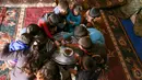 Beberapa cucu dari Abderrazaq Khatoun berbagi makanan di dalam tenda di desa Harbanoush, Suriah, 11 Maret 2021. Mengungsi dari rumah asalnya di provinsi Hama, Khatoun dan 30 anggota keluarga yang masih hidup mendirikan empat tenda di sebidang tanah yang dikelilingi pohon zaitun (Ahmad al-ATRASH/AFP)