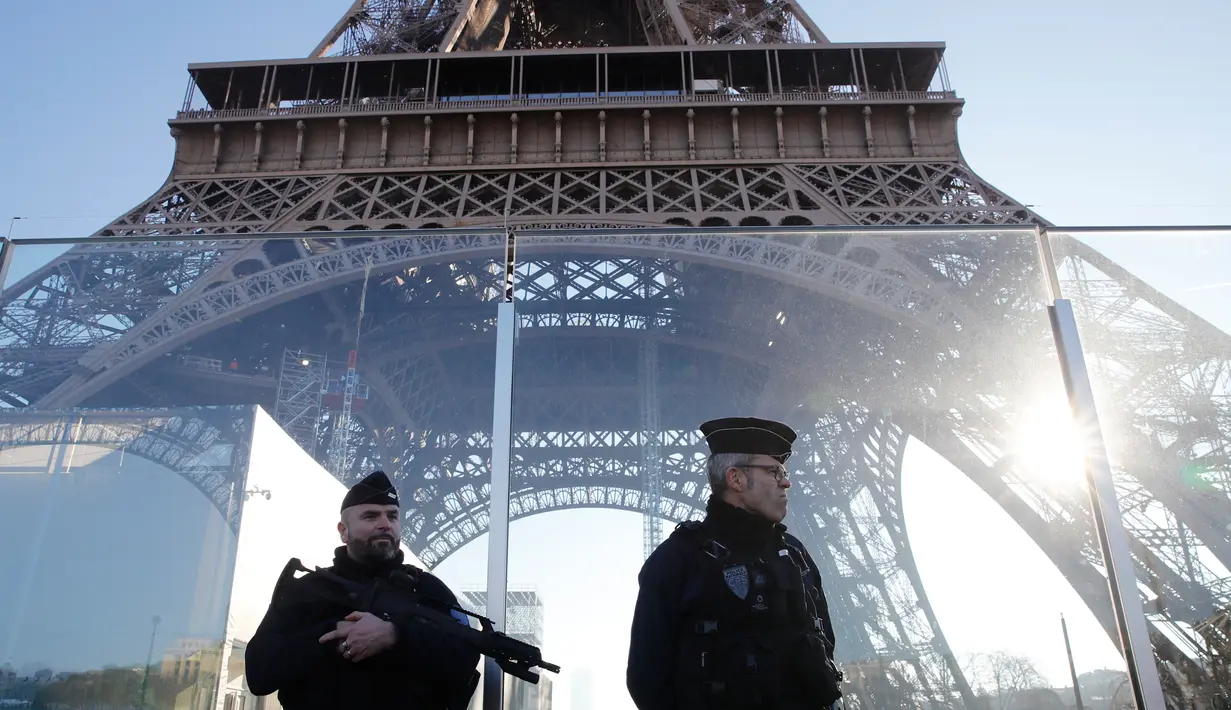 Polisi berpatroli di dekat Menara Eiffel yang dilindungi tembok kaca antipeluru di Paris,  Senin (30/12/2019). Pemerintah Prancis akan mengerahkan 100.000 petugas polisi untuk mengamankan ruang publik pada perayaan malam Tahun Baru di tengah aksi mogok yang sedang berlangsung. (AP/Christophe Ena)