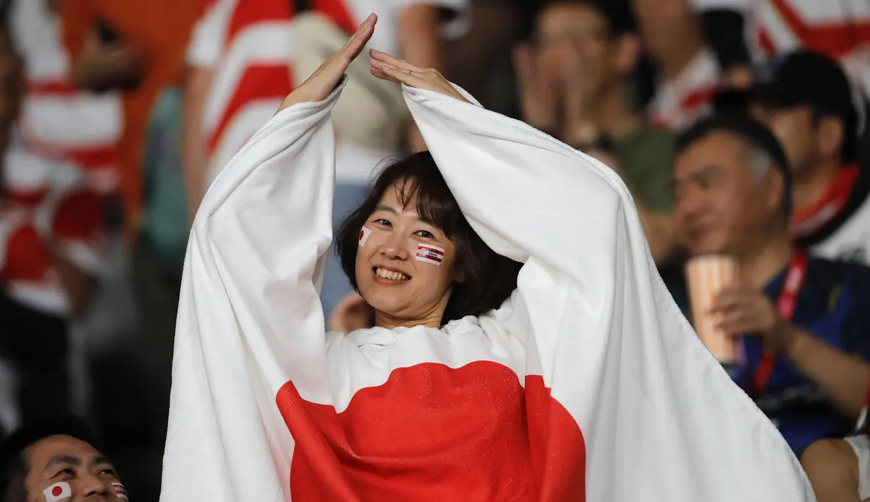 Fans wanita mengenakan kostum bergambar bendera Jepang bersorak sebelum pertandingan melawan Rusia pada pembukaan Rugby World Cup Pool A  di Stadion Tokyo (20/9/201). Rugby World Cup diselenggarakan dari 20 September hingga 2 November 2019. (AP Photo/Jae Hong)