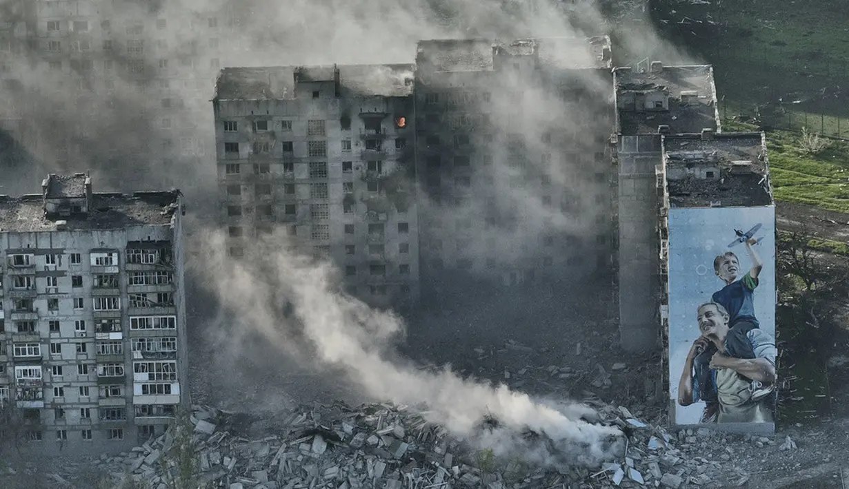 <p>Asap mengepul dari sebuah gedung di Bakhmut, tempat pertempuran terberat dengan pasukan Rusia di wilayah Donetsk, Ukraina, Rabu (26/4/2023). (AP Photo/Libkos)</p>