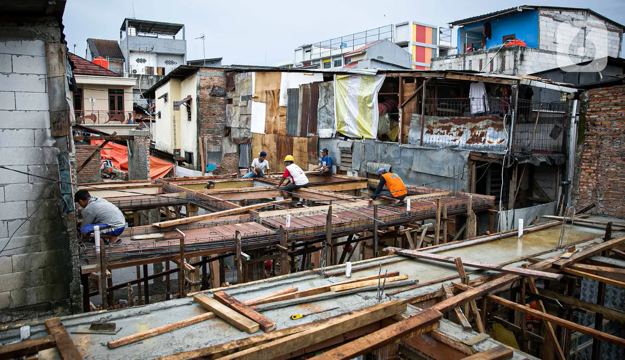 Para pekerja menyelesaikan pembangunan rumah panggung di dekat bantaran Kali Ciliwung, Kampung Melayu, Jakarta, Rabu (7/4/2021). Pemerintah Provinsi DKI Jakarta melakukan renovasi terhadap 40 hunian warga Kampung Melayu menjadi rumah panggung. (Liputan6.com/Faizal Fanani)