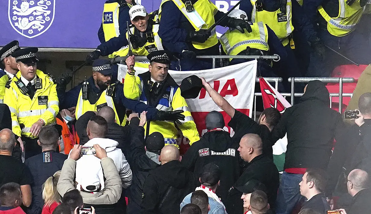 Suporter Hungaria bentrok dengan polisi saat dimulainya laga Kualifikasi Piala Dunia 2022 melawan Inggris di Stadion Wembley, Rabu (13/10/2021) dini hari WIB. Bentrokan terjadi saat polisi berusaha menangkap penonton yang melakukan pelecehan rasial terhadap petugas stadion. (Nick Potts/PA via AP)