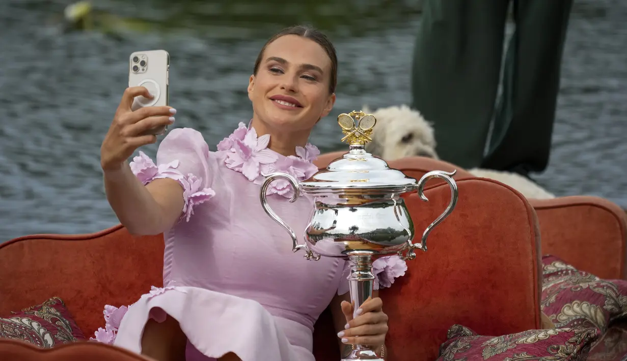 Petenis Belarusia, Aryna Sabalenka berselfie dengan trofi kejuaraan tenis Australia Open 2023 di atas gondola di Royal Botanic Garden di Melbourne (29/1/2023). Sabalenka menjadi petenis Belarusia kedua yang memenangi Australia Open setelah Victoria Azarenka pada 2012 dan 2013. (AP Photo/Dita Alangkara)