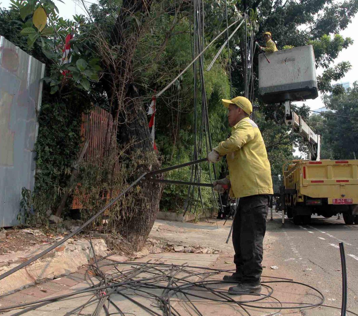Kabel-kabel semrawut di Jakarta akhirnya mulai ditertibkan. Hal itu terlihat di Jalan Yusuf Adiwinata, Menteng, Jakarta Pusat, pada Jumat (11/8/2023). Petugas Dinas Bina Marga DKI tampak menggunting kabel-kabel semrawut yang menjuntai.